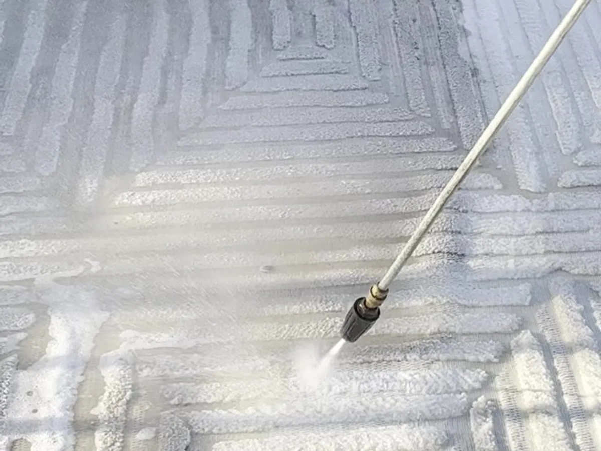 Pressure washing spray rinsing grime from a textured outdoor surface