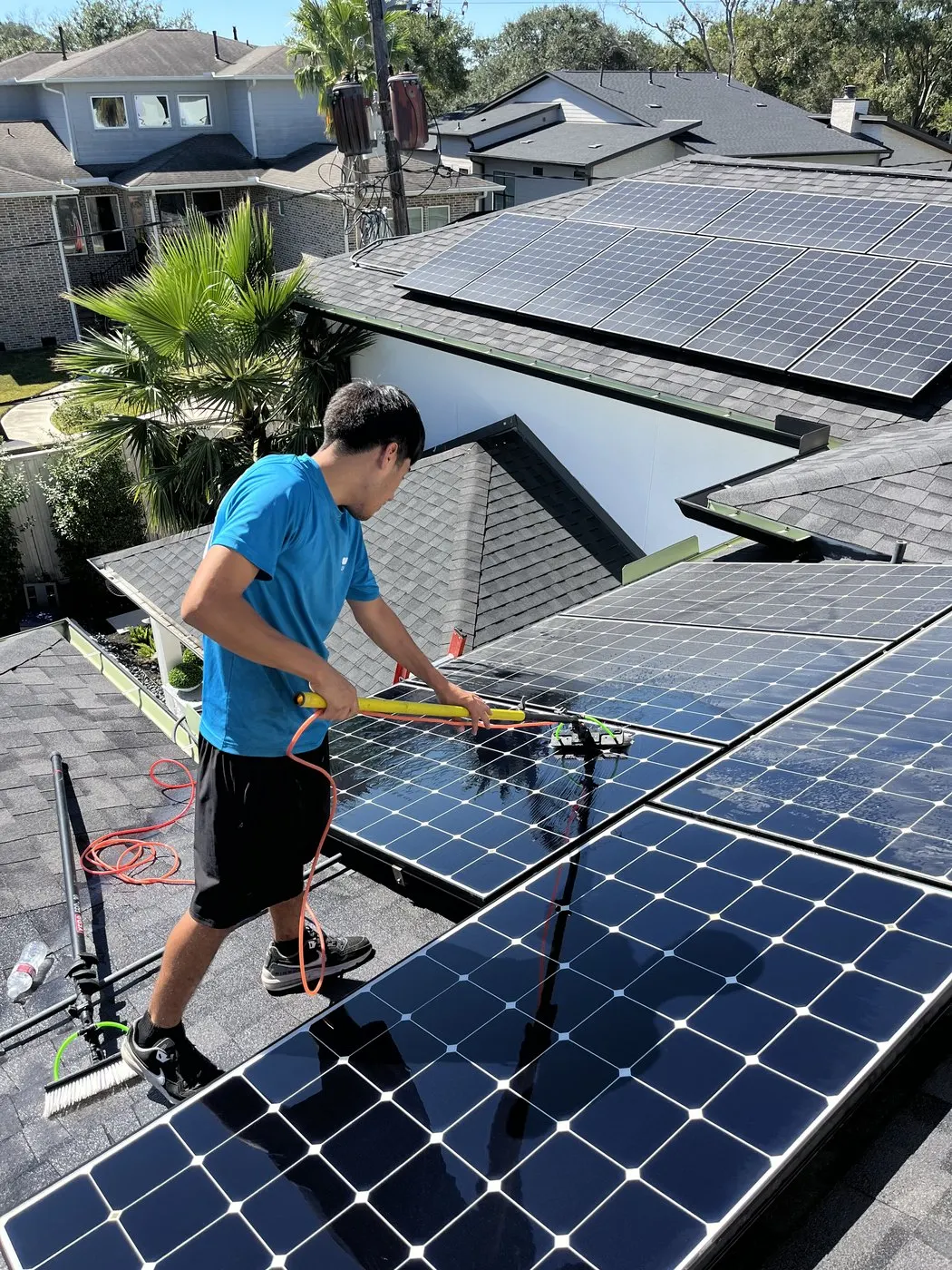 Technician cleaning rooftop solar panels on a Houston home.