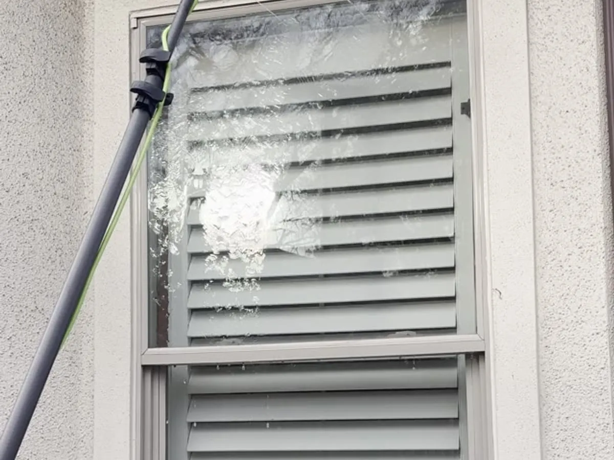 Water-fed pole brush cleaning a residential exterior window